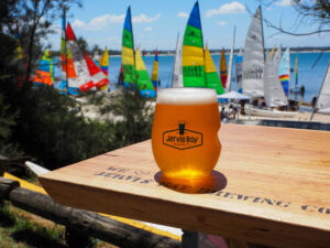 Glass of beer sitting on a table in front of Sailing boats